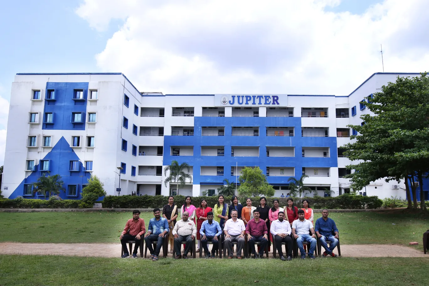 A group seated for a photo on the lawn in front of the Jupiter college building.