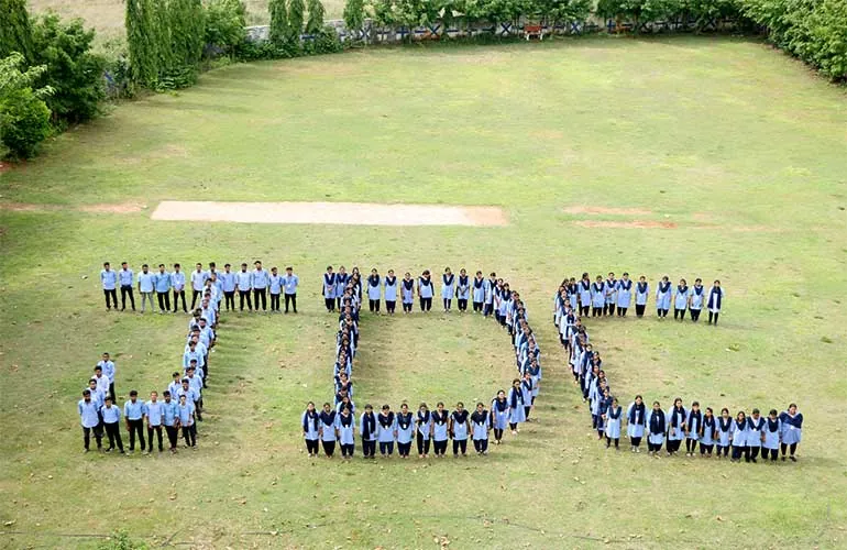 Students standing on the lawn in a formation spelling the letters JDC.