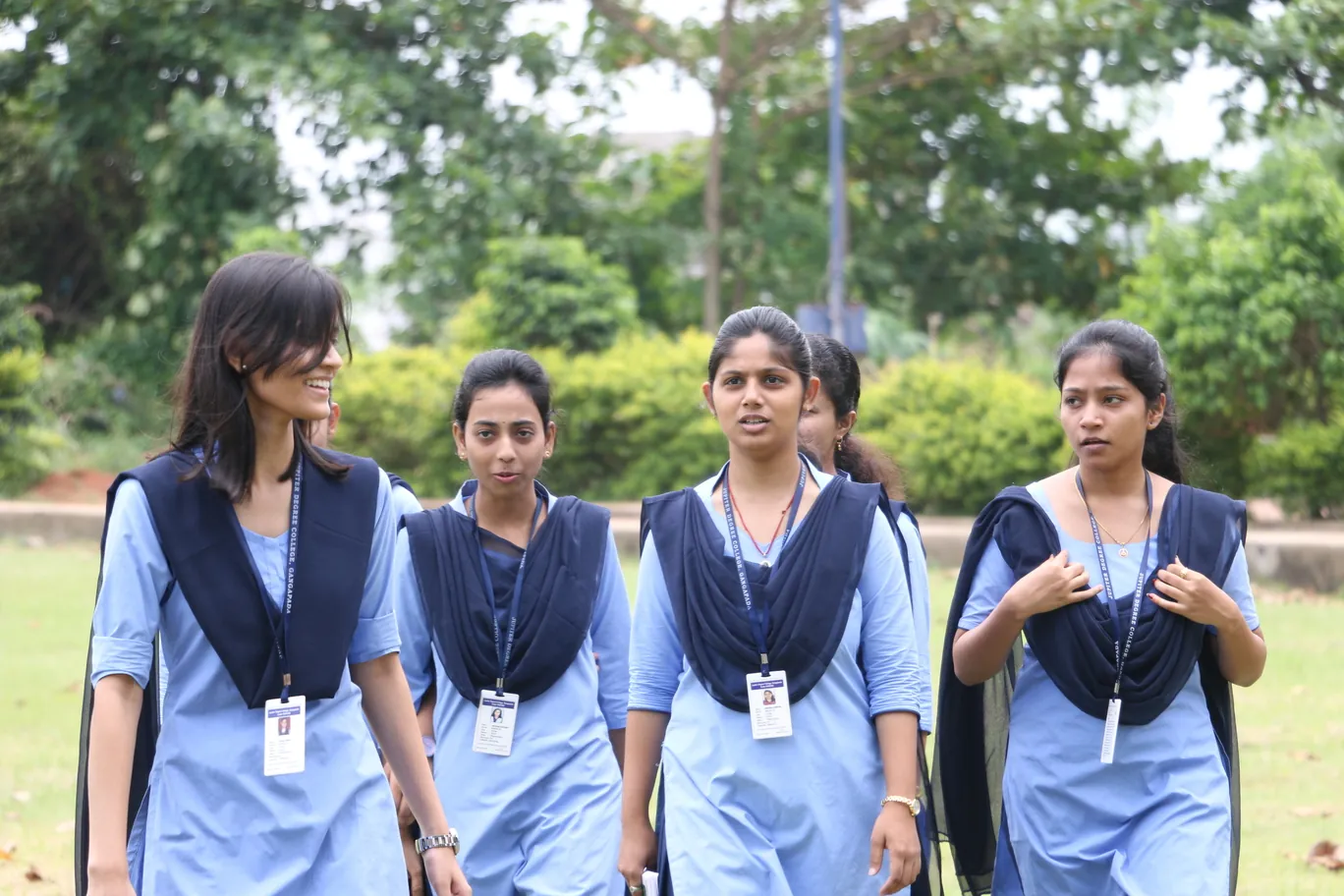 Four students in uniform standing together on the campus.