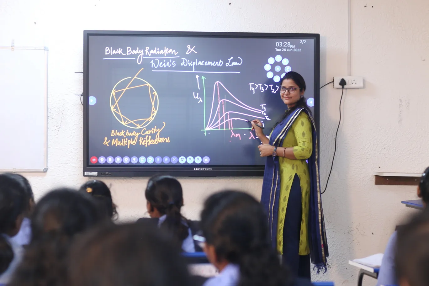 A teacher explaining a physics diagram on an interactive smart board.