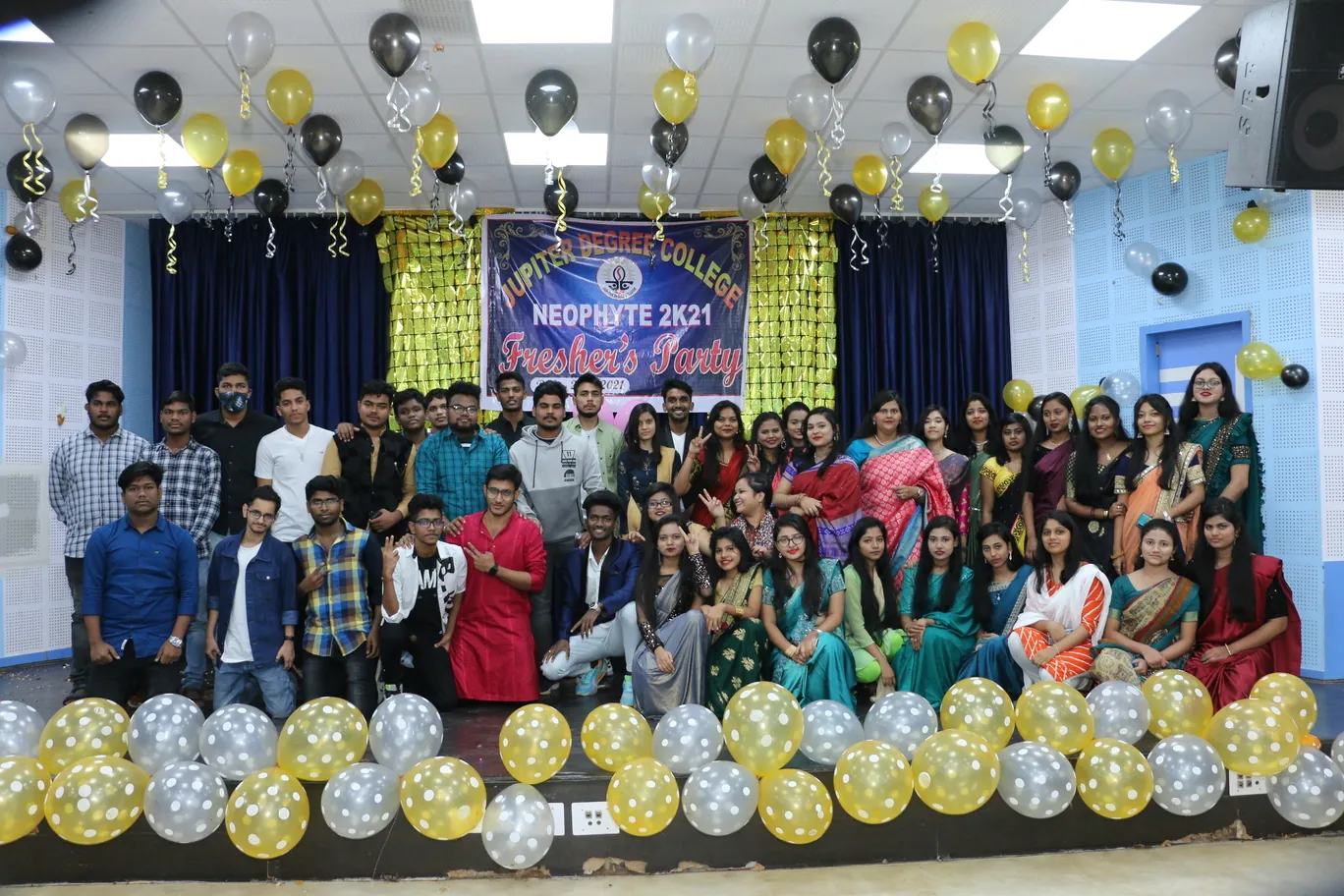 Students and faculty on stage at the Neophyte 2021 freshers’ event, decorated with balloons.