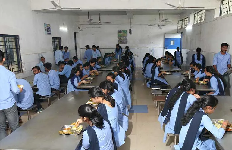 Students in uniform eating together at long tables in the dining hall.