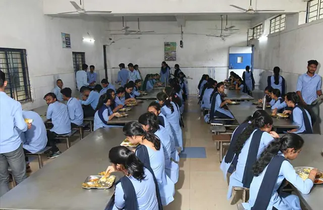 Students in uniform eating together at long tables in the dining hall.