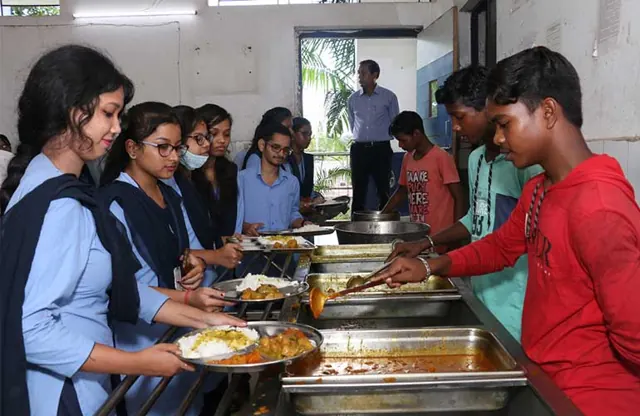Students being served a hot meal at the dining-hall counter.