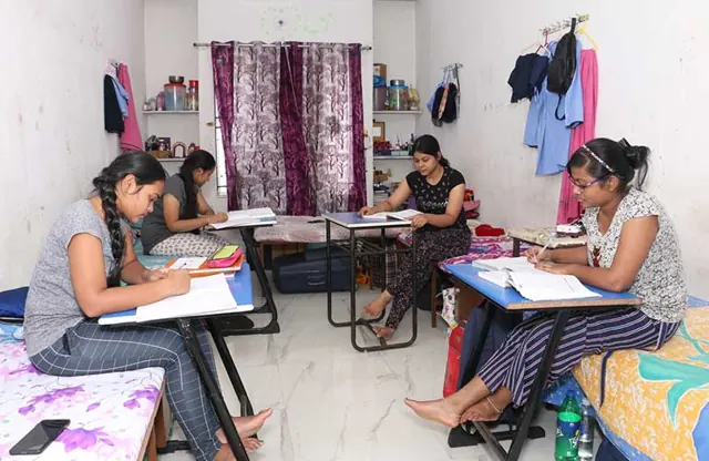 Students studying at their desks in a girls’ hostel room.
