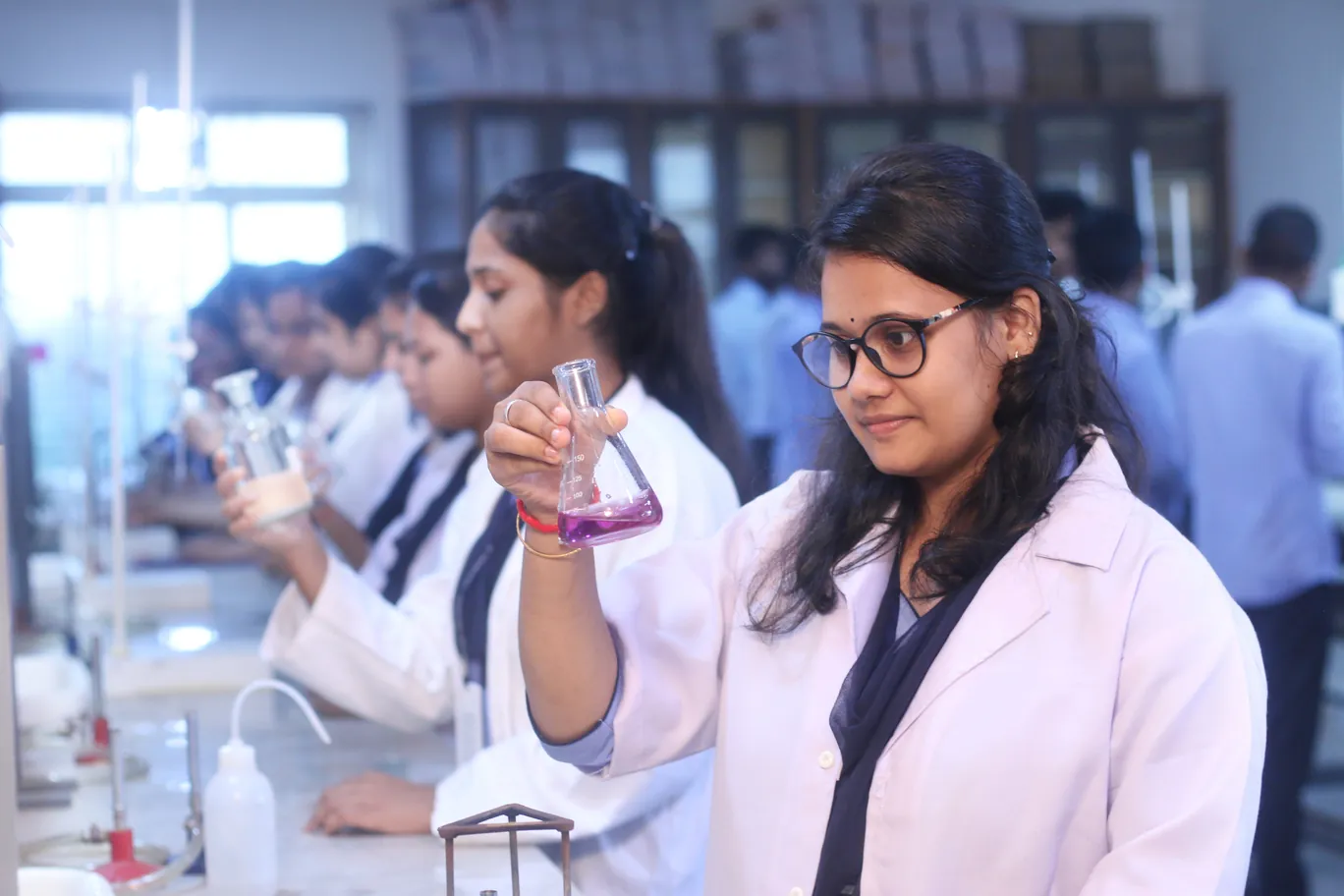 A student in a lab coat holding up a flask during a chemistry practical.