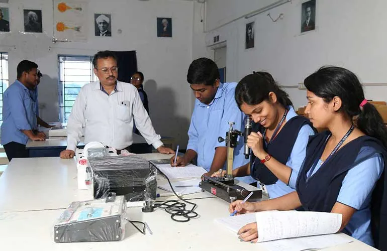 A faculty member guiding students through a physics experiment.