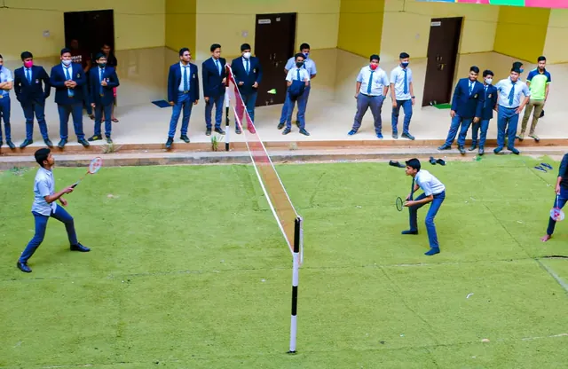 Students playing a game on the campus court while others watch.